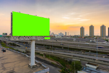 Large blank billboard pole beside highway in city at dusk background with green screen