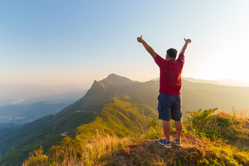 Senior retired man raise hand after success climbed mountain