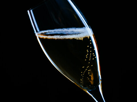 Glass Of Sparkling Champagne. Champagne is sparkling in a champagne glass isolated against a black background