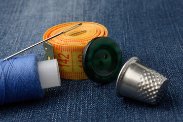 close-up of measuring tape of spool of thread and thimble buttons.