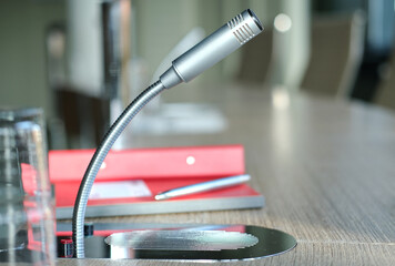 Nahaufnahme eines freigestellten Mikrofons mit Sprechanlage und Büromaterialien – selektiver...