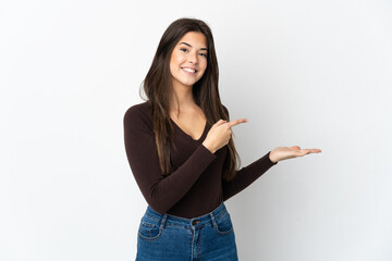 Teenager Brazilian girl isolated on white background holding copyspace imaginary on the palm to...