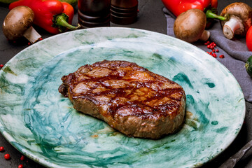 juicy Ribeye steak on beautiful green plate on black concrete table