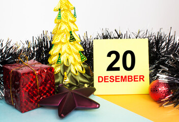 Christmas tree decorated with toys and tinsel, gift boxes and Yellow sticker with text 20 december