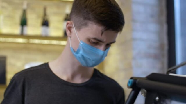 Concentrated Young Male Barista In Covid Face Mask Preparing Milk For Cappuccino In Cafe. Portrait Of Professional Bartender In Coffee Shop On Coronavirus Pandemic Lockdown. Cinema 4k ProRes HQ.