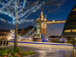 Tower Bridge of London illuminated at night and a decorated tree in Christmas holiday on the...