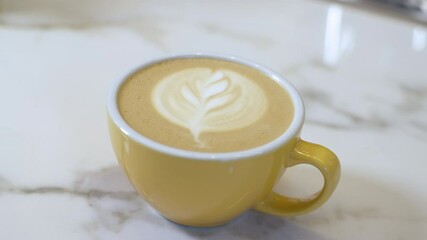 Close-up of yellow cup with cappuccino on table. Male Caucasian hand moving hot drink. Unrecognizable man serving delicious coffee in cafe or restaurant. Cinema 4k ProRes HQ.