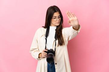 Young photographer Brazilian girl isolated on pink background making stop gesture and disappointed