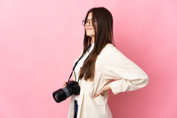 Young photographer Brazilian girl isolated on pink background suffering from backache for having made an effort