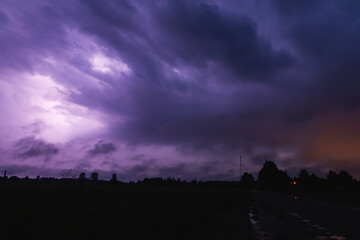 Naklejka na ściany i meble clouds over the city at night lightning dark gravel road purple violet lit up thunder