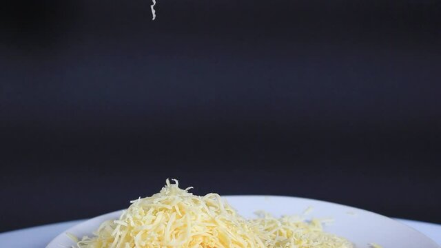 Hard grated cheese is sprinkled on top of the plate on a black background. close-up, selective focus.