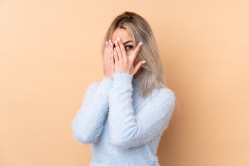 Teenager girl over isolated background covering eyes and looking through fingers