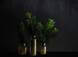 spruce branches in glass jars with gold glitter