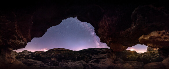 Naklejka premium Night panoramic inside a megalithic monument, with engravings and geoglyphs carved in the rock. Observing the milky way and the moon from inside the Neolithic arch.