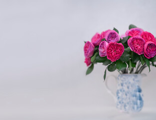 Pink roses in jug on light background at home stock photo. Beautiful bouquet with roses on light background