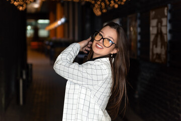 Portrait of young beautiful brunette woman in classic suit and glasses outdoors.