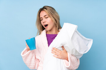 Fototapeta premium Teenager Russian girl in pajamas isolated on blue background