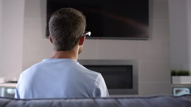 Behind look of man on couch with 3d glasses swiping as if he is looking at holographic screen for you to insert your graphics into.