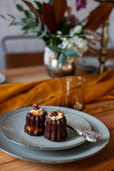 chocolate muffins in ceramic plates with fork and knife, textile napkin and flowers on wooden table