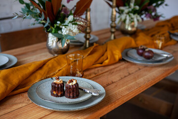 chocolate muffins in ceramic plates with fork and knife, textile napkin and flowers on wooden table