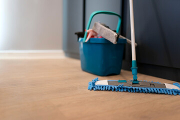 Fototapeta premium Cleaning concept. Mop and plastic bucket with cleaning products on the floor