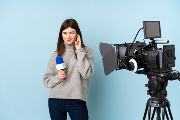 Young reporter woman holding a microphone and reporting news with fingers crossing