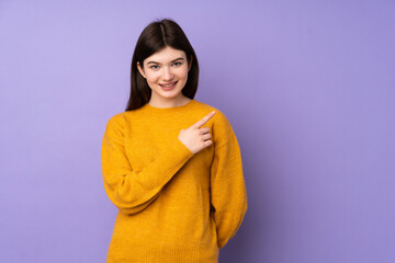 Fototapeta premium Young Ukrainian teenager girl over isolated purple background pointing to the side to present a product