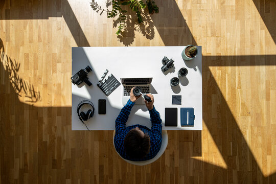 Close up top view shot of film maker sitting on desk cleaning lens with floating sun