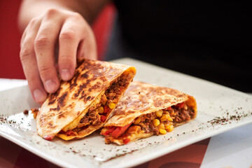 Mexican quesadilla with chicken, cheese and peppers on square plate