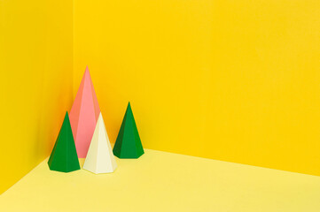Multi-colored paper pyramids on yellow background