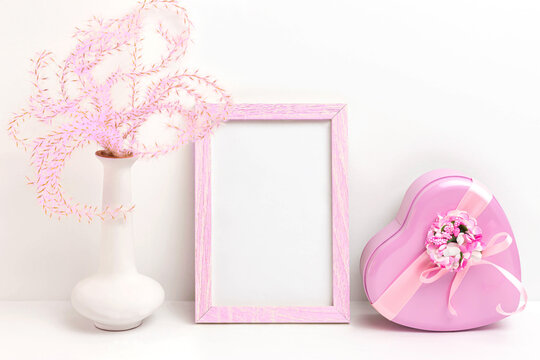 Photo frame mockup with plant in vase and heart-shaped gift