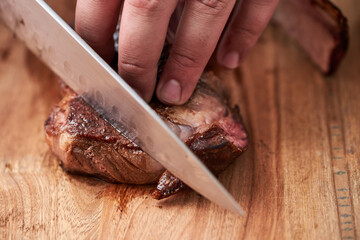Cooking juicy beef steak by chef hands on dark black background with space for text menu or recipe