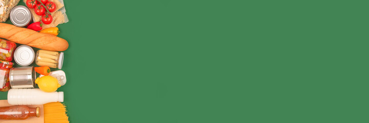 Banner with different groceries, food donations on green background with copy space - pasta, fresh vegatables, canned food, baguette, cooking oil, tomatoes, cheese. Food bank, food delivery concept