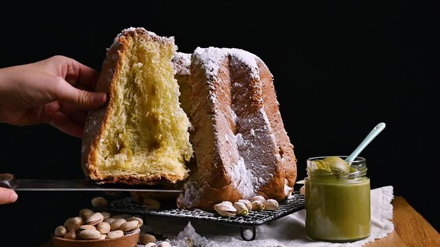 Pandora is an Italian Christmas bread. Sweet pastries from northern Italy with pistachio cream. The woman cuts off a piece of Pandoro. High quality 4k footage