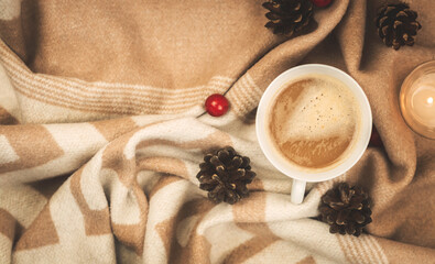 Cup of latte, dinner in bed by candlelight on a warm cozy plaid, decorations, pine cones and berries, toned