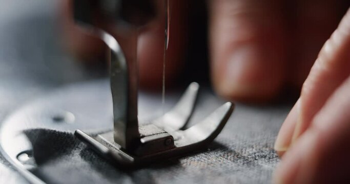 Cinematic macro shot of sewing machine stitching thread on fine quality fabric for creation custom haute couture apparel in traditional tailoring atelier. Concept of handmade, couturier and tradition.