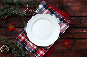 Tavolino natalizio con piatto bianco vuoto e decorazioni natalizie. Sfondo di legno. Vista...