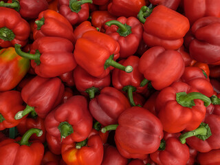 A background of a large number of large pods of sweet red pepper (Capsicum annuum). Background from vegetables on a shop window. Harvesting red pepper
