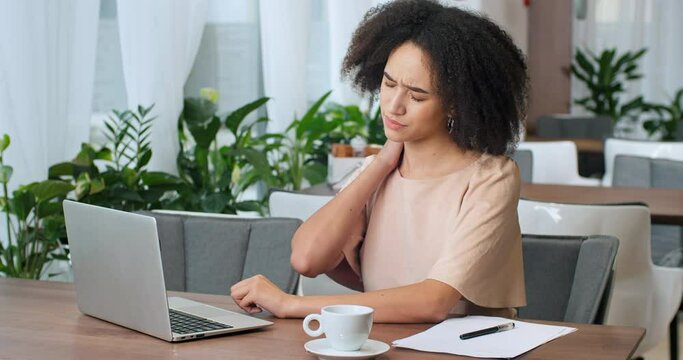 Side view young business woman mixed lady millennial foreign afro american female student freelance meager working remotely in cafe feeling headache suffering from back pain stress fatigue pressure