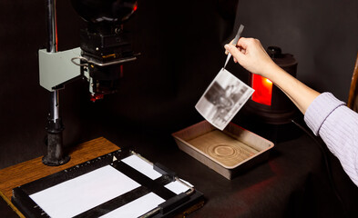 Analog photo printing. The photographer prints a black and white photograph. Photolaboratory. Red light