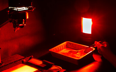Analog photo printing. The photographer prints a black and white photograph. Photolaboratory. Red...