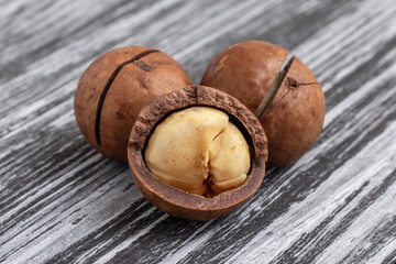 Three macadamia nuts on black wooden table close-up.