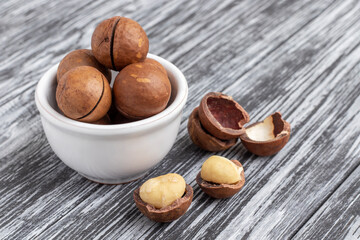 Macadamia nuts in white bowl on black wooden table.
