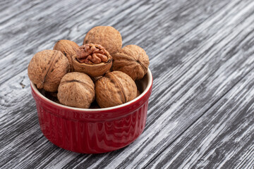 Walnuts in a red bowl on a black wooden table.