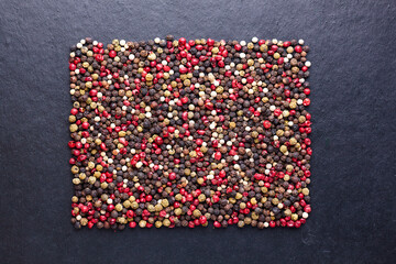 Squared mix of pepper seeds, spicy and condiment ingredients on black background