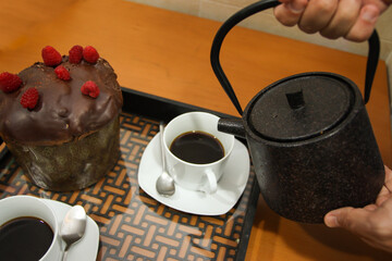 A tray with a couple of coffee cups and a chocolate cake and a coffee pot