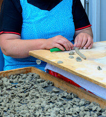 hands of a woman making traditional italian pasta called gray orecchiette from ash dough at Bari, Italy