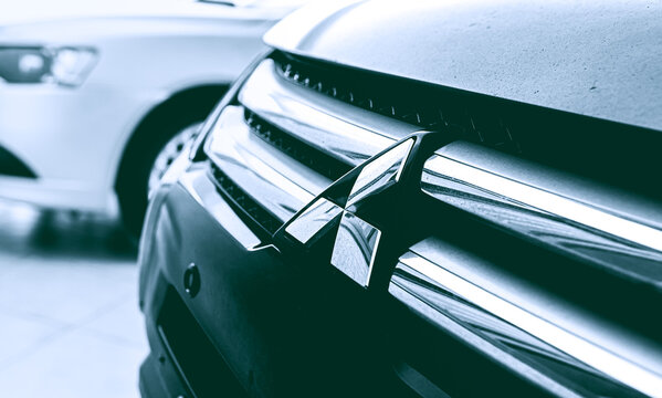 Mitsubishi Motors. Carros, autom&oacute;veis, editorial. Foto da logo da empresa japonesa Mitsunishi Motors. Parte dianteira de um ve&iacute;culo Eclipse Cross, ano 2019; e ao fundo um Lancer GT, ano 2015.