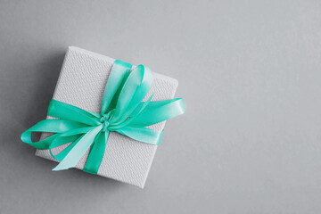 The gray gift box is tied with a mint satin ribbon. Gray is the popular color of 2021.
