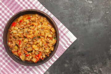 top view roasted eggplant salad in bowl on pink white checkered tablecloth on dark background with copy space